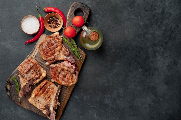 grilled veal steaks on a cutting board with spices on a stone background  with copy space for your text