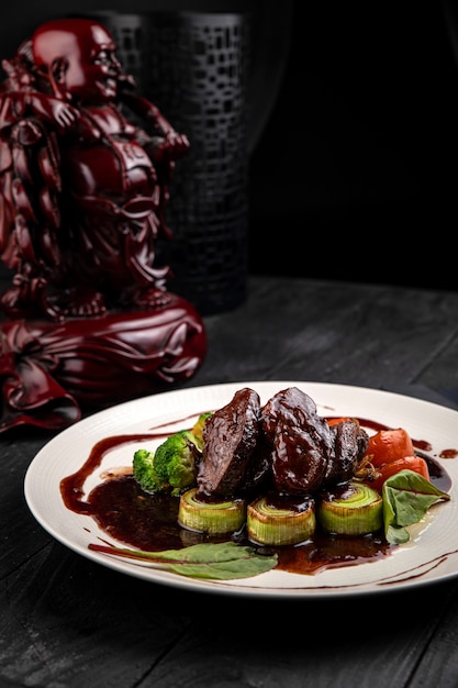 Grilled veal with sauce and broccoli on a dark table