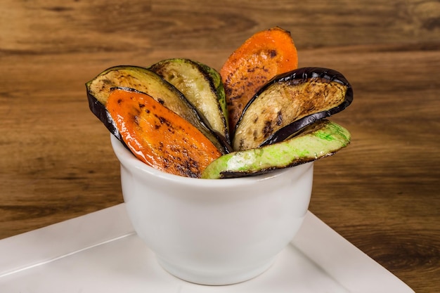 Grilled vegetable salad with zucchini eggplant and carrots served in a white bowl selective focus