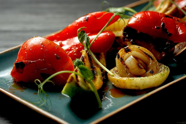 Grilled vegetables on a blue plate on a dark background. Vegetarian food