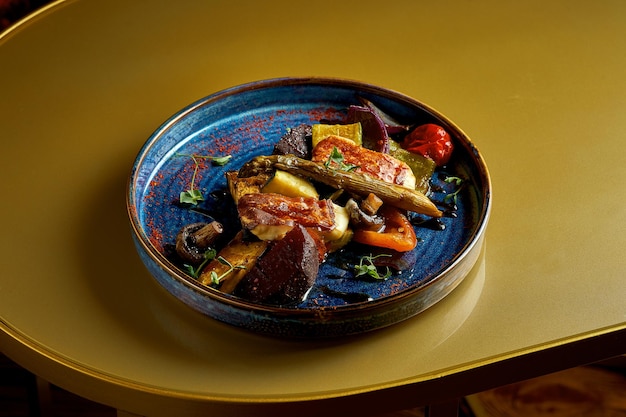 Grilled vegetables in a blue plate on a gold background