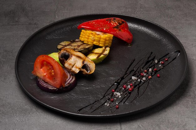 Grilled vegetables on a dark plate garnished with pepper and salt