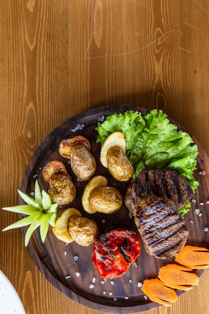 Verdure grigliate e un pezzo di deliziosa carne alla griglia su un tavolo di legno