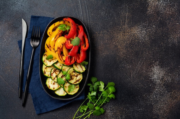 写真 ズッキーニのグリル野菜、赤と黄色のコショウ、コリアンダーの花束を皿に、サラダを炭火でバーベキューグリルラックに。バーベキューのコンセプト。