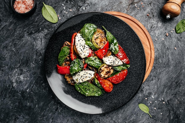 Grilled vegetables with spinach leaves and feta cheese on a dark background Restaurant menu dieting cookbook recipe top view