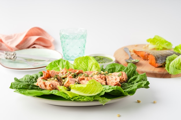 Grilled wild salmon and lettuce dish with green pesto, linen, cutlery, plate, glass of water