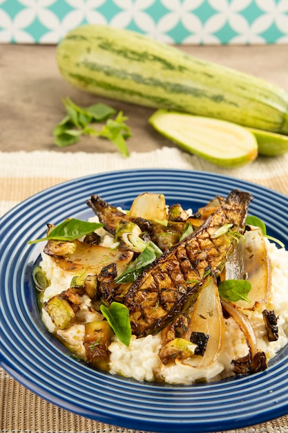 Grilled zucchini, rice, onion and basil over a blue dish with raw zucchini