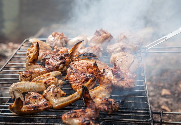 Grillen van gekruide kip in rooster op houtskool bbq. Ondiepe DOF.