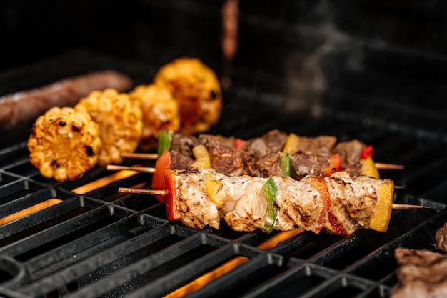 Grilling chicken skewers and corn on a barbecue