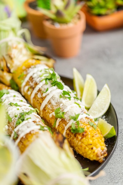 Grilling mexican street corn elote garnished with spices and
fresh cilantro on a serving plate.