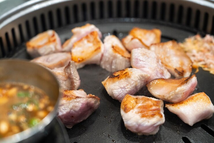 Photo 한국 식당 에서 철로 된 bbq 보드 에 돼지고기 를 그릴 것