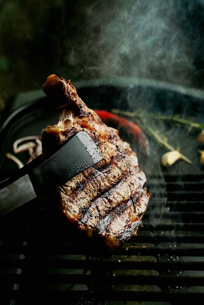 Photo grilling rib eye steak at home. natural smoke. summer grill, cooking at home concept