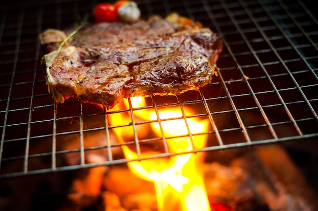 Grilling T Bone Steak on flaming grill