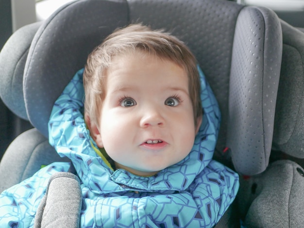 Grimacing child in a car seat. Child safety in the child's car seat during sleep.