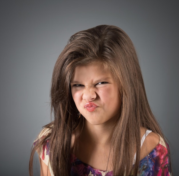 Grimacing girl studio shot gray background