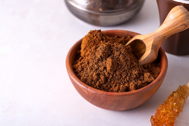 Grinded coffee in a wooden bowl with brown sugar stick