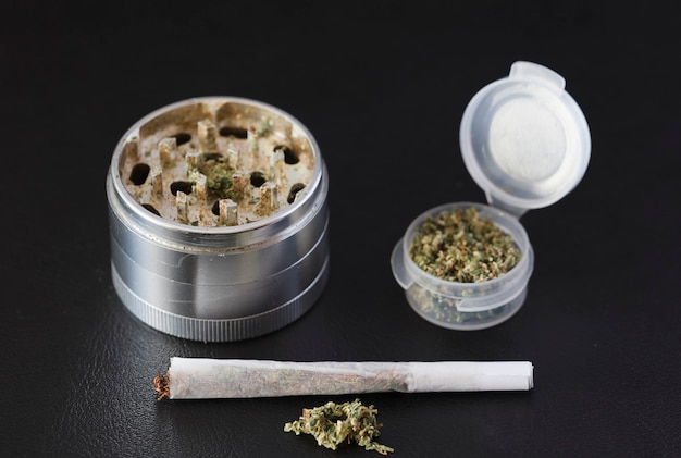 Grinder voor marihuana met porro en containerdispenser donkere achtergrond