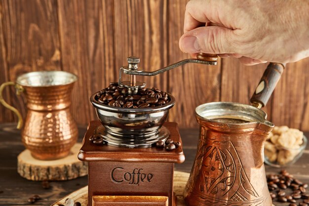 コーヒー豆をビンテージのコーヒーグラインコーヒーメーカーと銅のカップに粉する