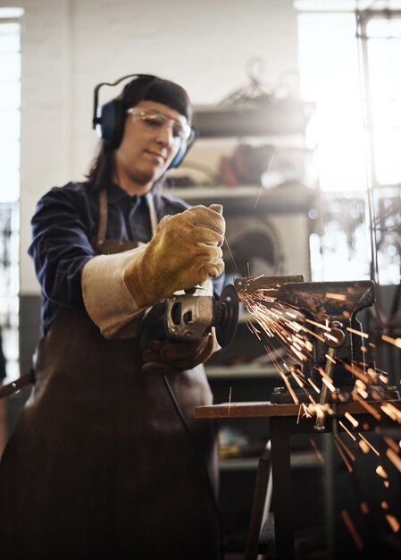 grinding it down cropped shot of an attractive young female artisan using an angle grinder in her workshop