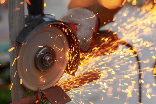 Grinding machine cuts metal sparks while working close-up