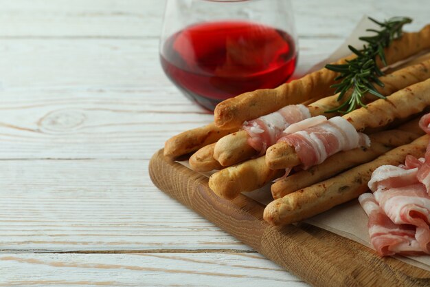 Grissini sticks met spek en wijn op witte houten achtergrond