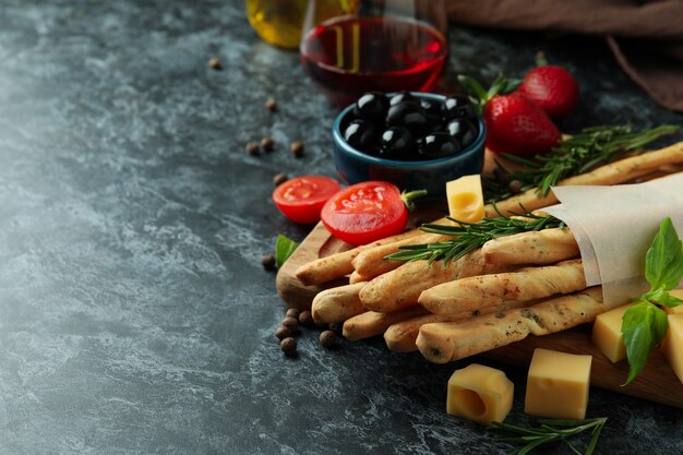 Grissini sticks, snacks and wine on black smokey background