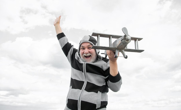 grizzle senior retired man mature man at retirement old man on sky background with toy plane outdoor