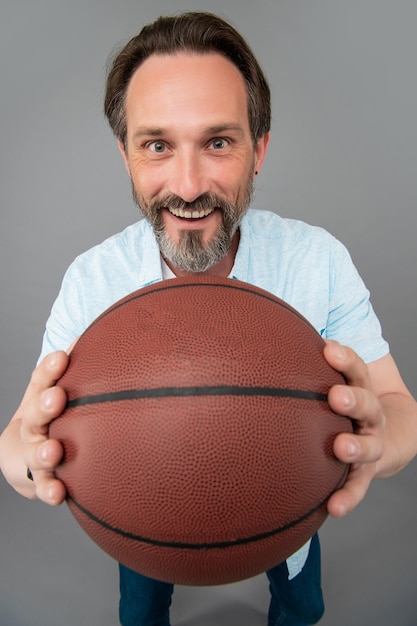 Grizzled basketball player training. guy has sport motivation. sport and hobby. selective focus. sport activity. happy senior man with basketball ball on grey background.