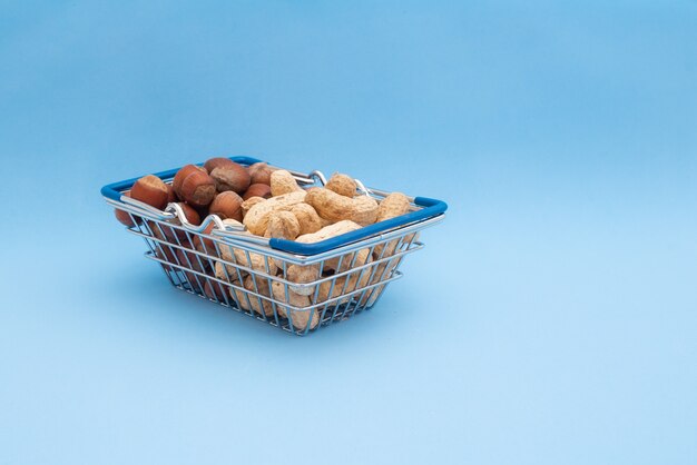 Grocery basket with peanuts and hazelnuts on a blue table