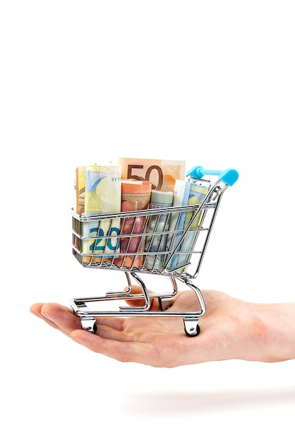 Grocery cart with euro bills with hand. Isolated on white. shopping, loan, money saving, pension, investments concept