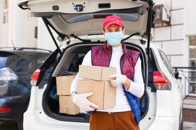 Grocery delivery man wearing medical gloves and face mask. Online shopping and delivery for grocerys, wine and food. Self Quarantine during coronavirus pandemic. Food delivery service courier