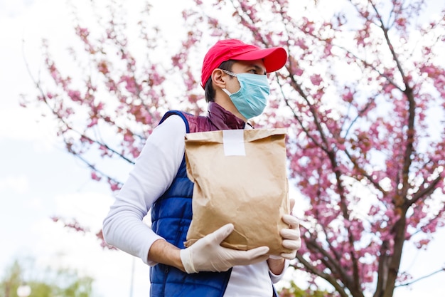 Grocery delivery man wearing medical gloves and face mask. Online shopping and delivery for grocerys, wine and food. Self Quarantine during coronavirus pandemic. Food delivery service courier