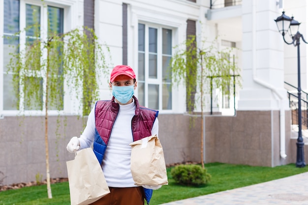 Grocery delivery man wearing medical gloves and face mask.\
online shopping and delivery for grocerys, wine and food. self\
quarantine during coronavirus pandemic. food delivery service\
courier