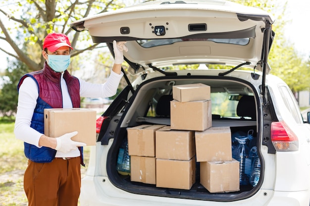 Photo grocery delivery man wearing medical gloves and face mask. online shopping and delivery for grocerys, wine and food. self quarantine during coronavirus pandemic. food delivery service courier