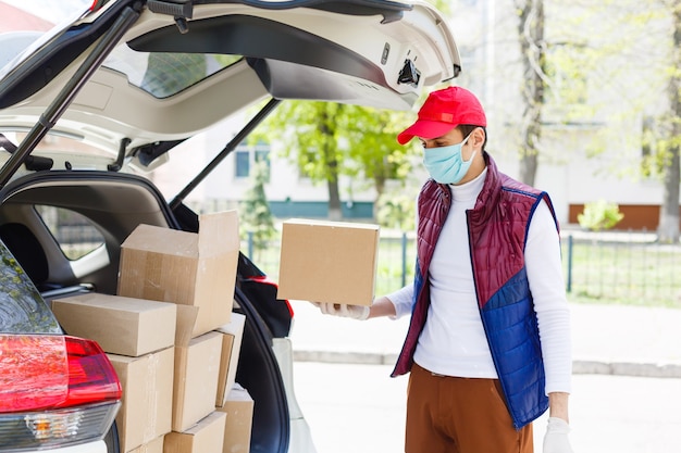 Grocery delivery man wearing medical gloves and face mask.\
online shopping and delivery for grocerys, wine and food. self\
quarantine during coronavirus pandemic. food delivery service\
courier