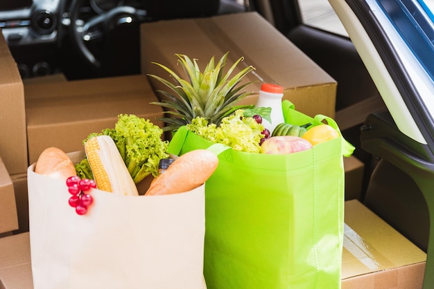 新鮮な野菜や果物、緑の布の袋に入った食料品サービス、後ろの車に木製のバスケットを入れて配達し、女性客に配達する準備ができています