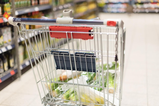 흐릿한 슈퍼마켓 배경에 음식이 가득 찬 식료품 쇼핑 카트 복사 공간 지속 가능한 라이프스타일 판매 할인 개념