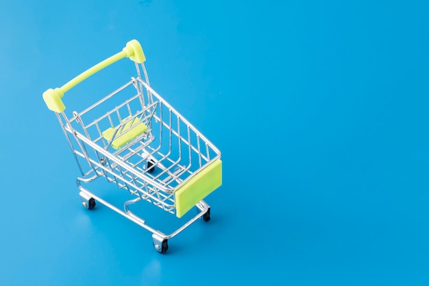 Grocery shopping in supermarket, cart basket on blue