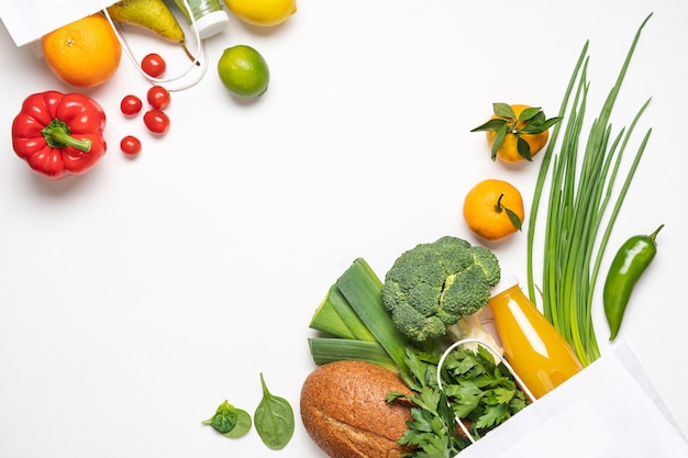 Grocery shopping  on white background. Vegetables, fruits, juice bottles and bread in paper bags