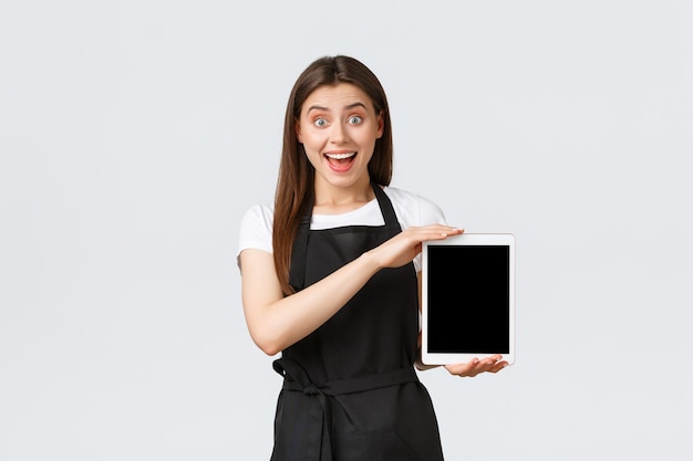 Работники продуктового магазина, малый бизнес и концепция кафе. Взволнованная продавщица, показывающая классную рекламу, улыбающаяся, пораженная, как показывает цифровой планшетный дисплей, стенд на белом фоне.