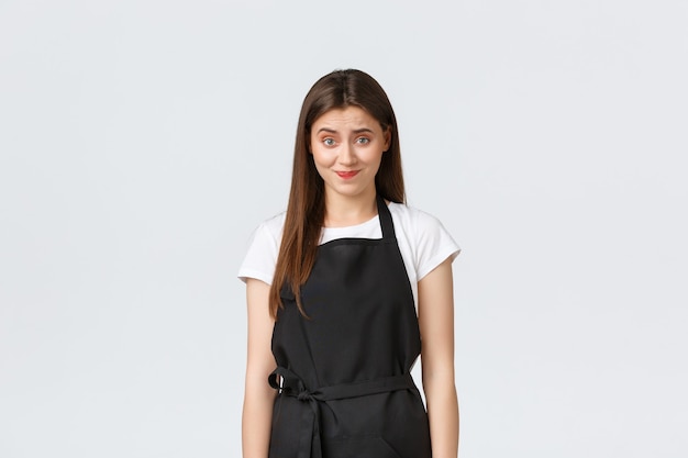 Grocery store employees, small business and coffee shops concept. Skeptical and awkward female barista smirk and looking uncomfortable as telling unpleasant news, white background.