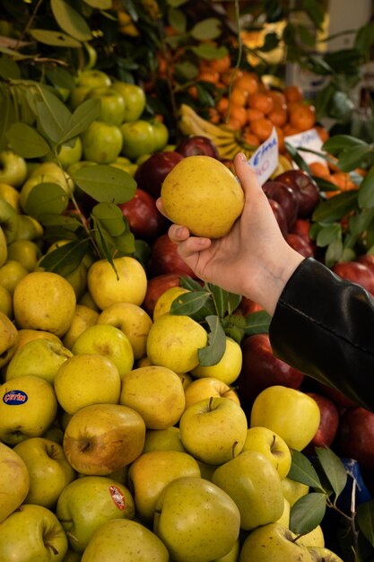 Продуктовый магазин со свежими здоровыми вегетарианскими фруктами и овощами Девушка выбирает яблоки