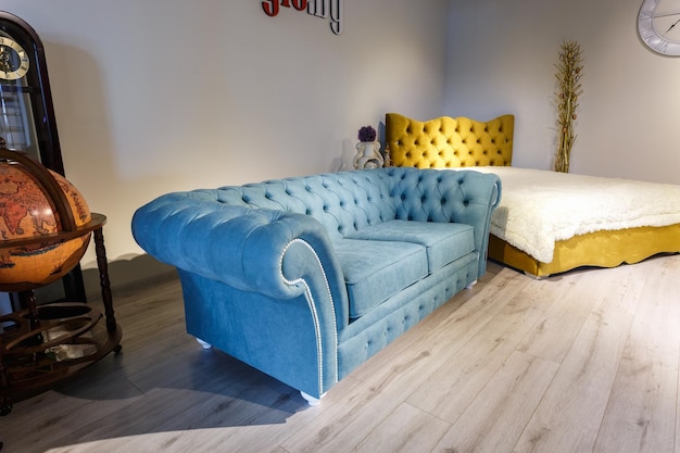 Grodno belarus december 2018 yellow leather bed and blue sofa\
in chester style for elite loft interior in expensive store\
showroom of furniture