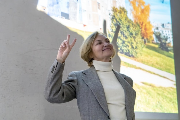 Grodno belarus june 012020 an elderly pretty woman stands on\
the stage and smiles against the background of a large screen\
speaker\'s speech at the film screening emotions on the face