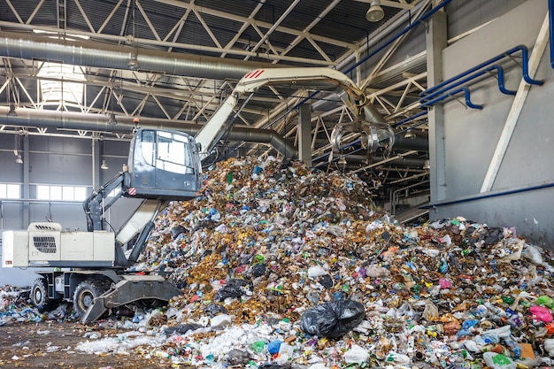 Photo grodno belarus may 2018 excavator on primary sorting of garbage at waste processing plant separate garbage collection recycling and storage of waste for further disposal