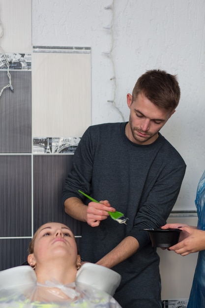 Grodno, Belarus - October 20, 2016: Keune brand technologist Artem Raychuk dyes the hair of a model on advertising workshop with the participation in the beauty salon Kolibri.