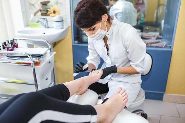 GRODNO BELARUS SEPTEMBER 2018 the master in black gloves in the salon makes manicure pedicure to the client