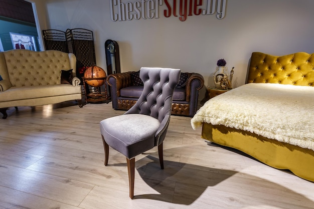 GRODNO WIT-RUSLAND DECEMBER 2018 bruine stoelbank en bed in chester-stijl voor elite loft-interieur in dure winkelshowroom van meubels