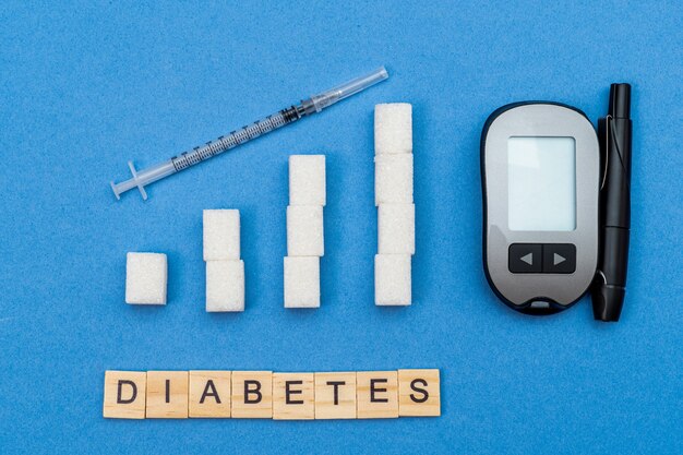 Foto groeiende, toenemende suikerkolommen, grafiek, spuit en woord diabetes op blauwe achtergrond
