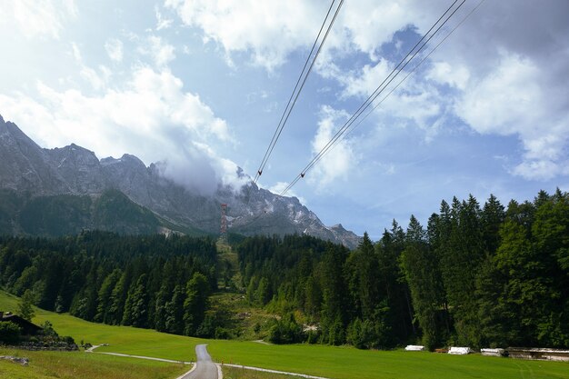 Foto groen alpenlandschap in het zomerseizoen. groene weiden. het pad dat naar de berg leidt, panoramisch uitzicht - hoogte bereikt door brand-kabelbanen